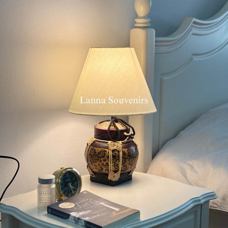 Handmade bamboo table lamp with beige shade on white bedside table next to clock and book