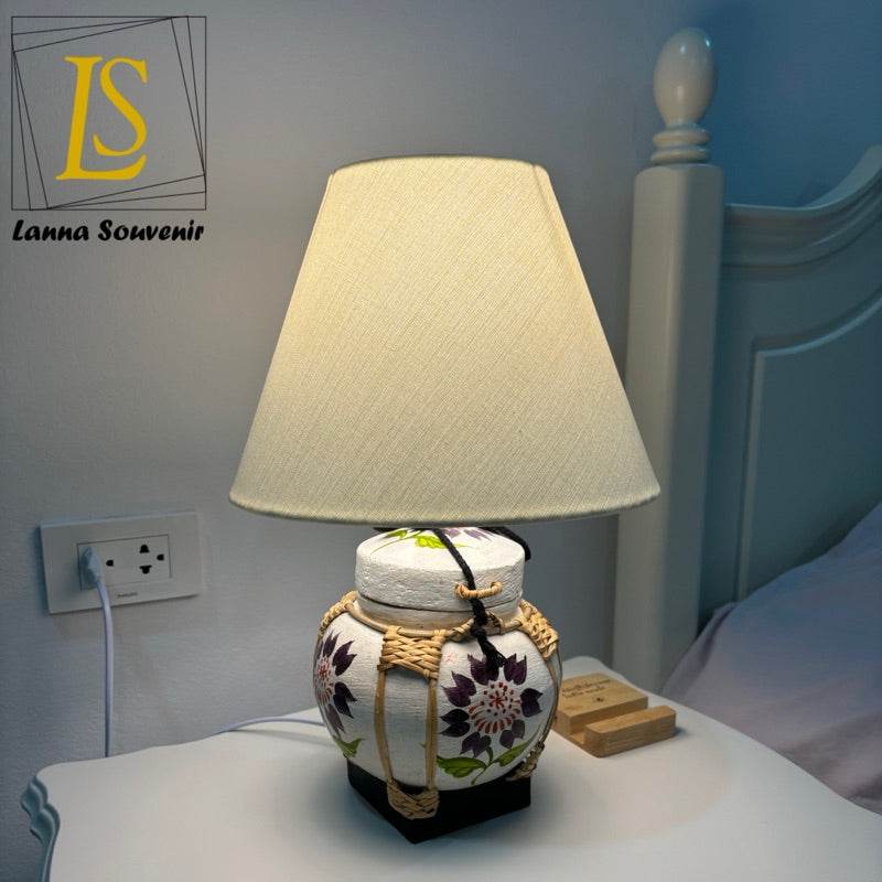 Handmade bamboo table lamp with floral design and beige lampshade on bedside table