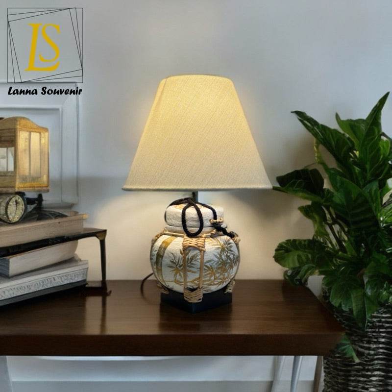 Handmade bamboo table lamp with fabric shade on wooden table next to green plant and books