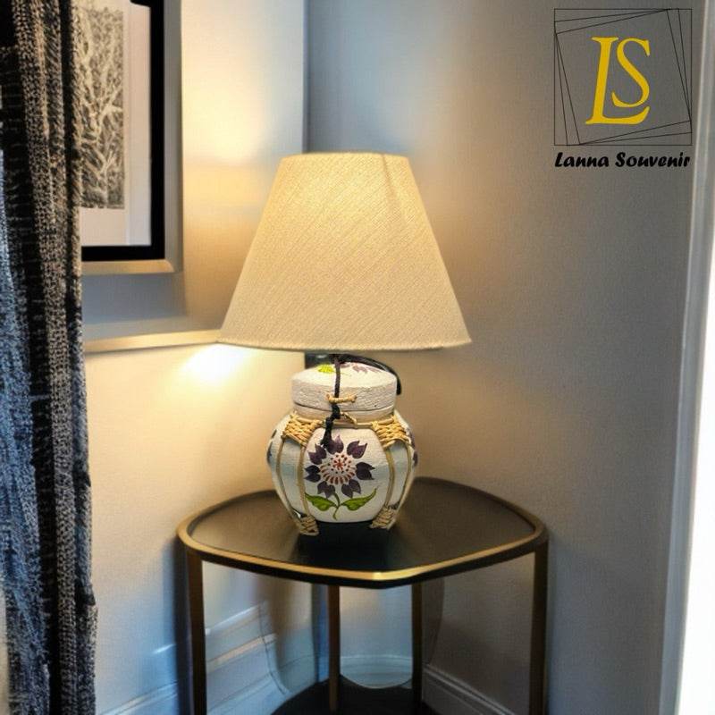 Handmade bamboo table lamp with floral ceramic base and beige fabric shade on wooden side table