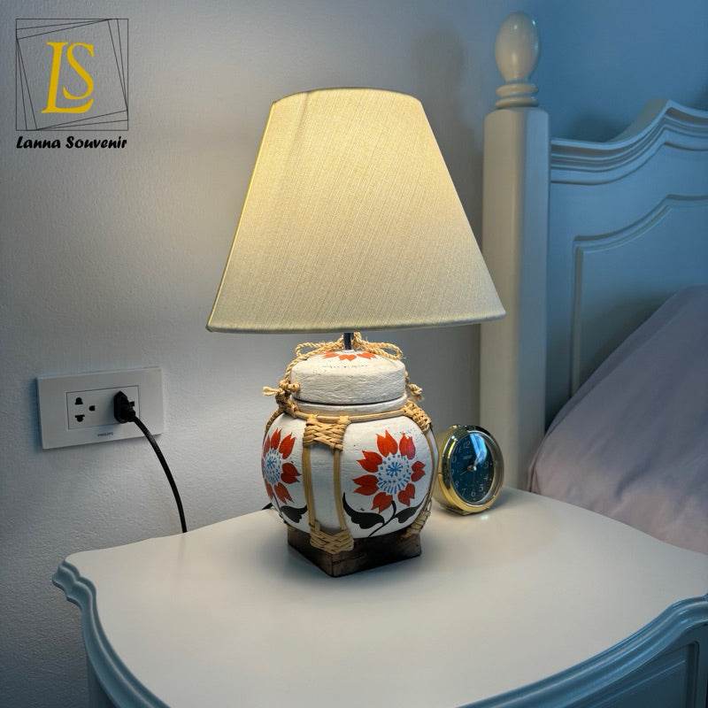 Handmade bamboo table lamp with floral design and beige shade on white bedside table