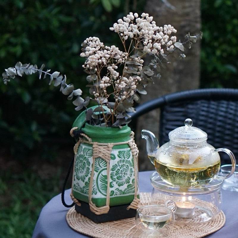 Handmade Thai rice basket used as a decorative green vase with dried flowers on an outdoor table