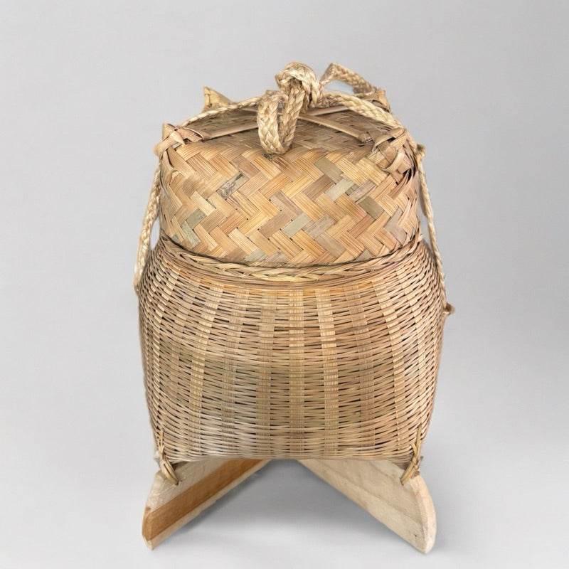 Handwoven bamboo sticky rice box from Thailand with natural fiber handles and a traditional design