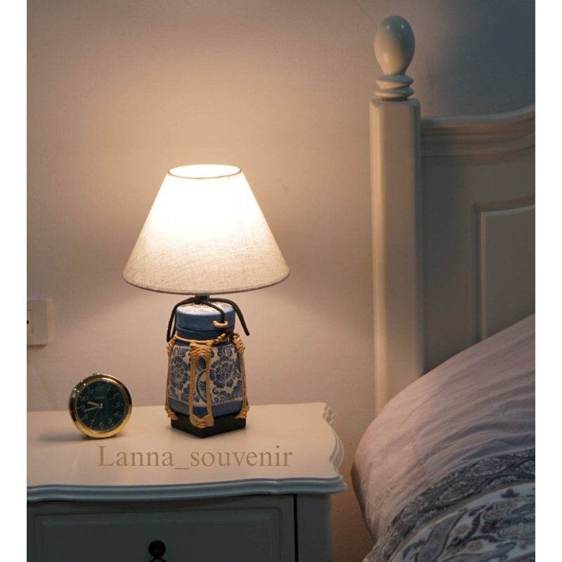 Handmade bamboo lamp for bedroom on a nightstand next to a bed with warm light