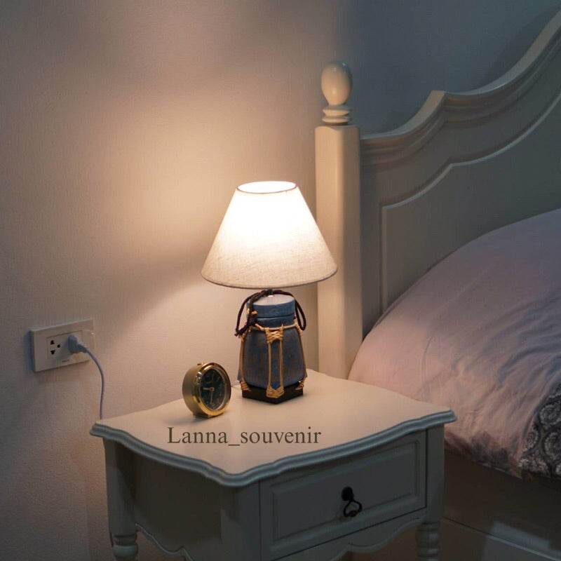 Handmade bamboo lamp for bedroom on white bedside table next to bed with warm light