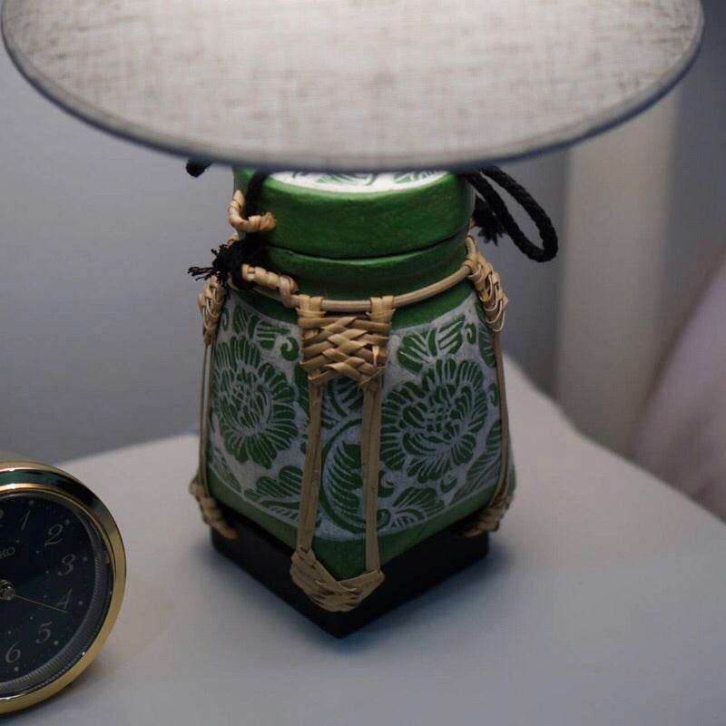 Handmade bamboo lamp for bedroom with green floral design and fabric shade on bedside table