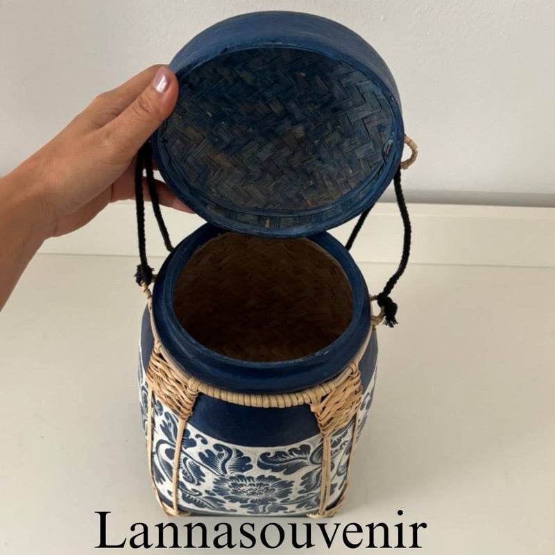Lanna storage jar with floral pattern in blue and natural tones, with a hand lifting the lid