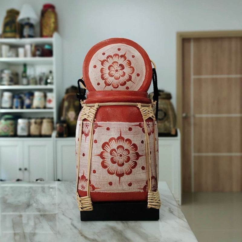 Lanna storage jar with floral pattern in red and beige with woven accents on kitchen countertop