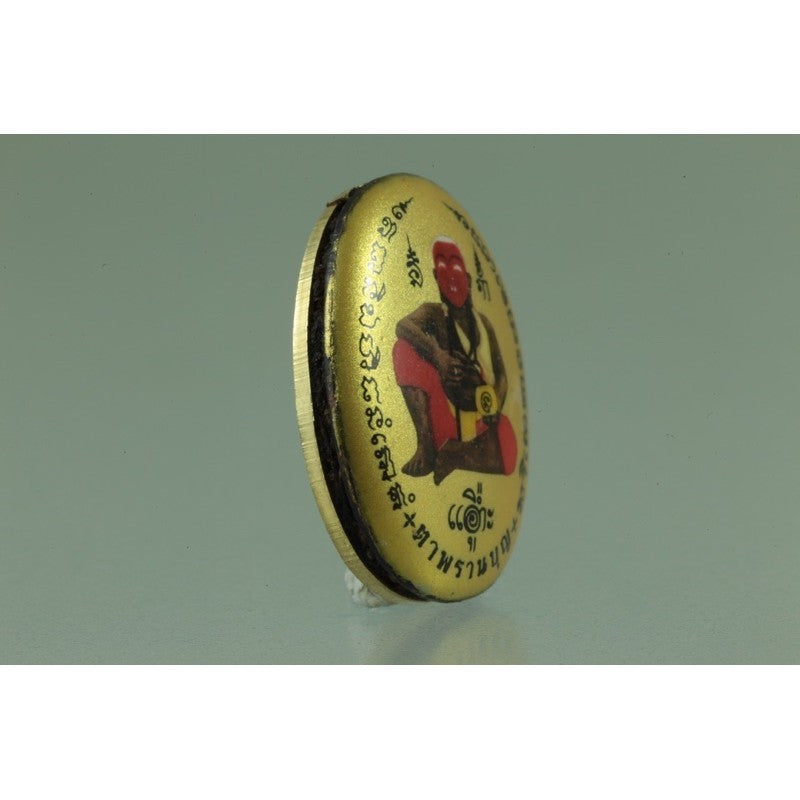 Golden oval amulet featuring Thai script and a red figure with Locket Ta Pran Boon golden back