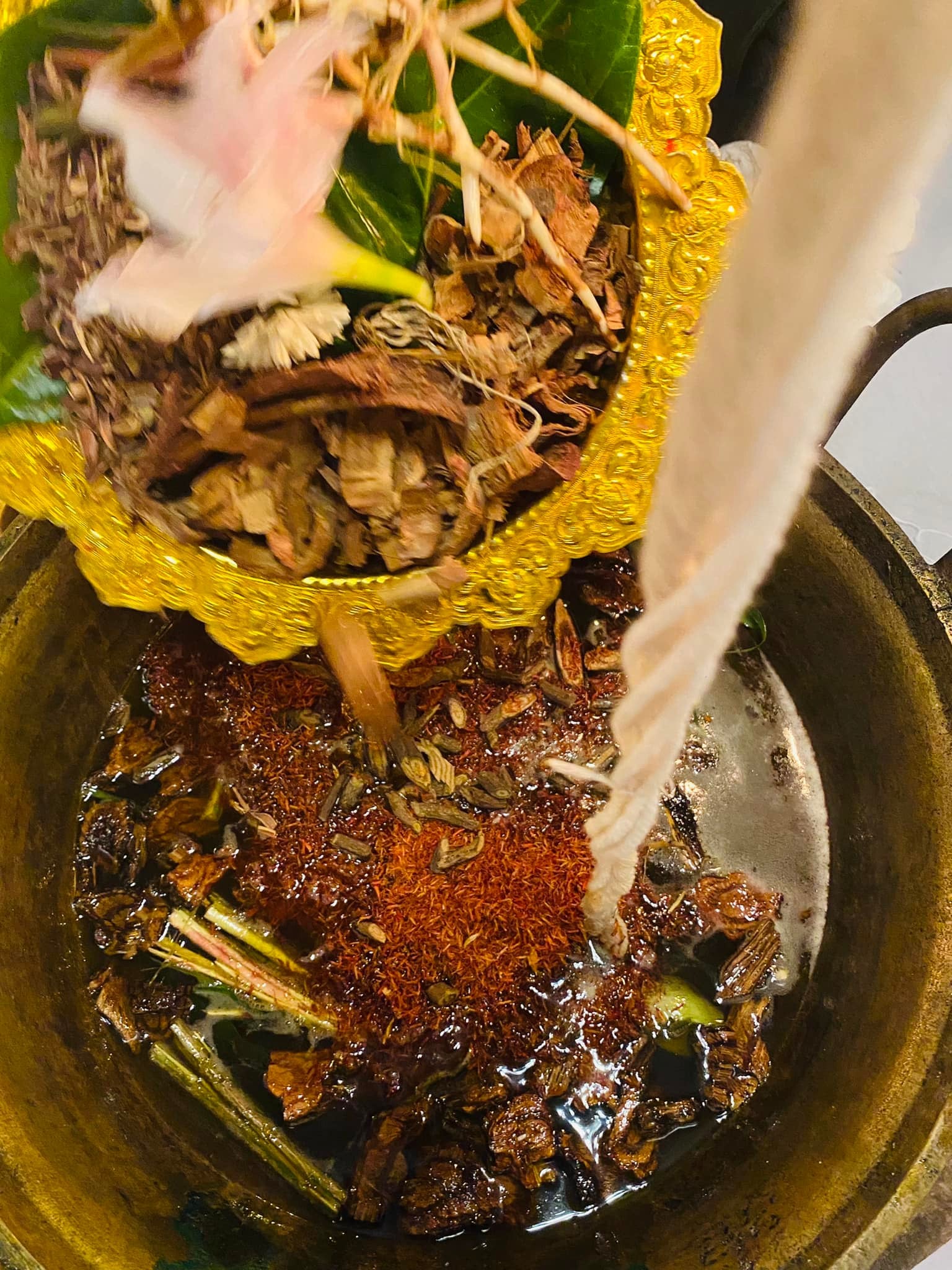 Lohit Sawat oil for attraction brewing in brass pot with herbs flowers and wood for Thai blessing ritual