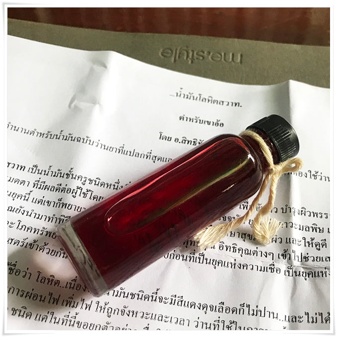 Small glass bottle of red oil with twine on paper label Lohit Sawat oil for attraction from Thai Blessing Co