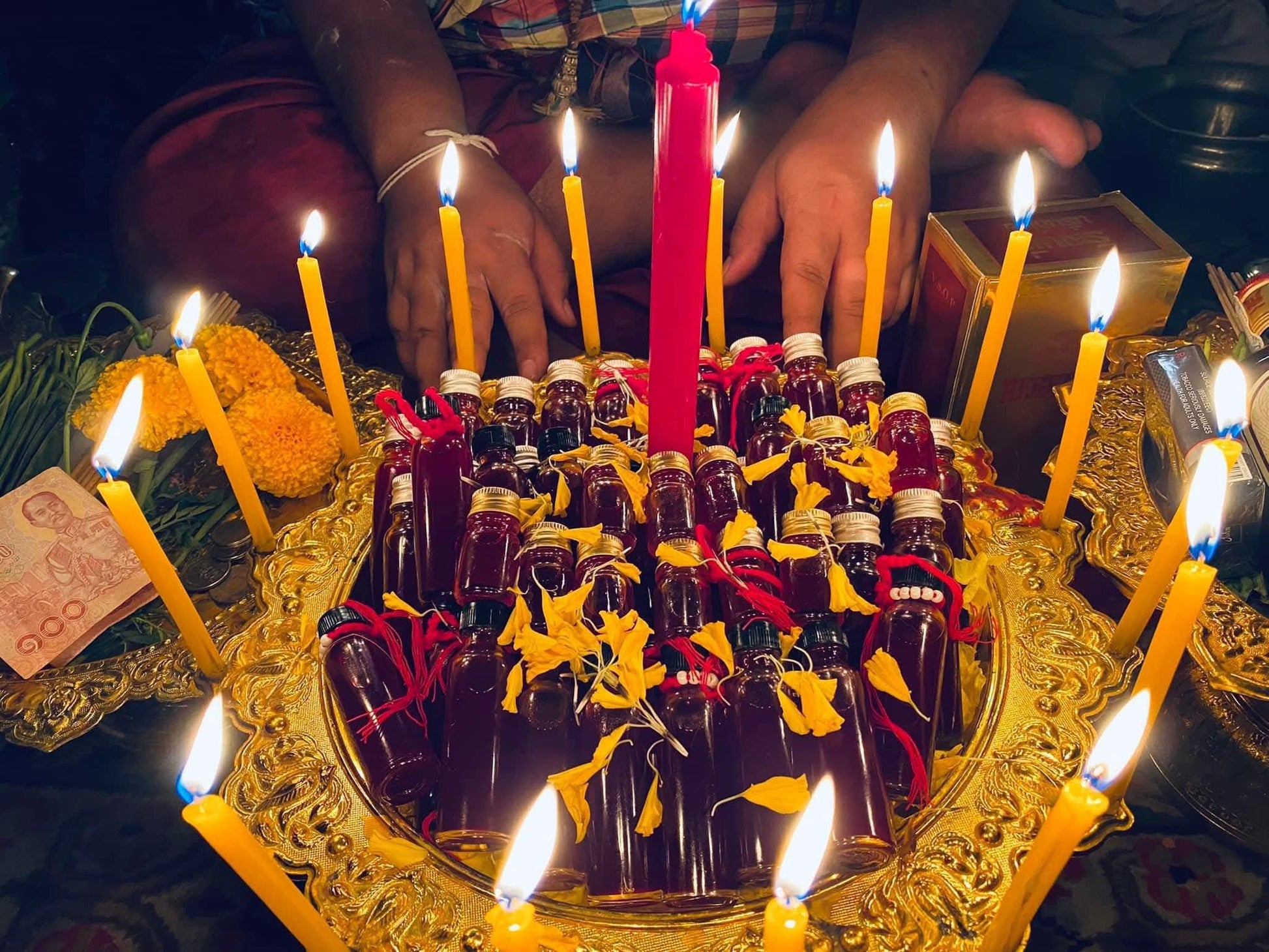Thai Blessing Co Lohit Sawat oil for attraction bottles on ornate gold tray with candles and marigolds