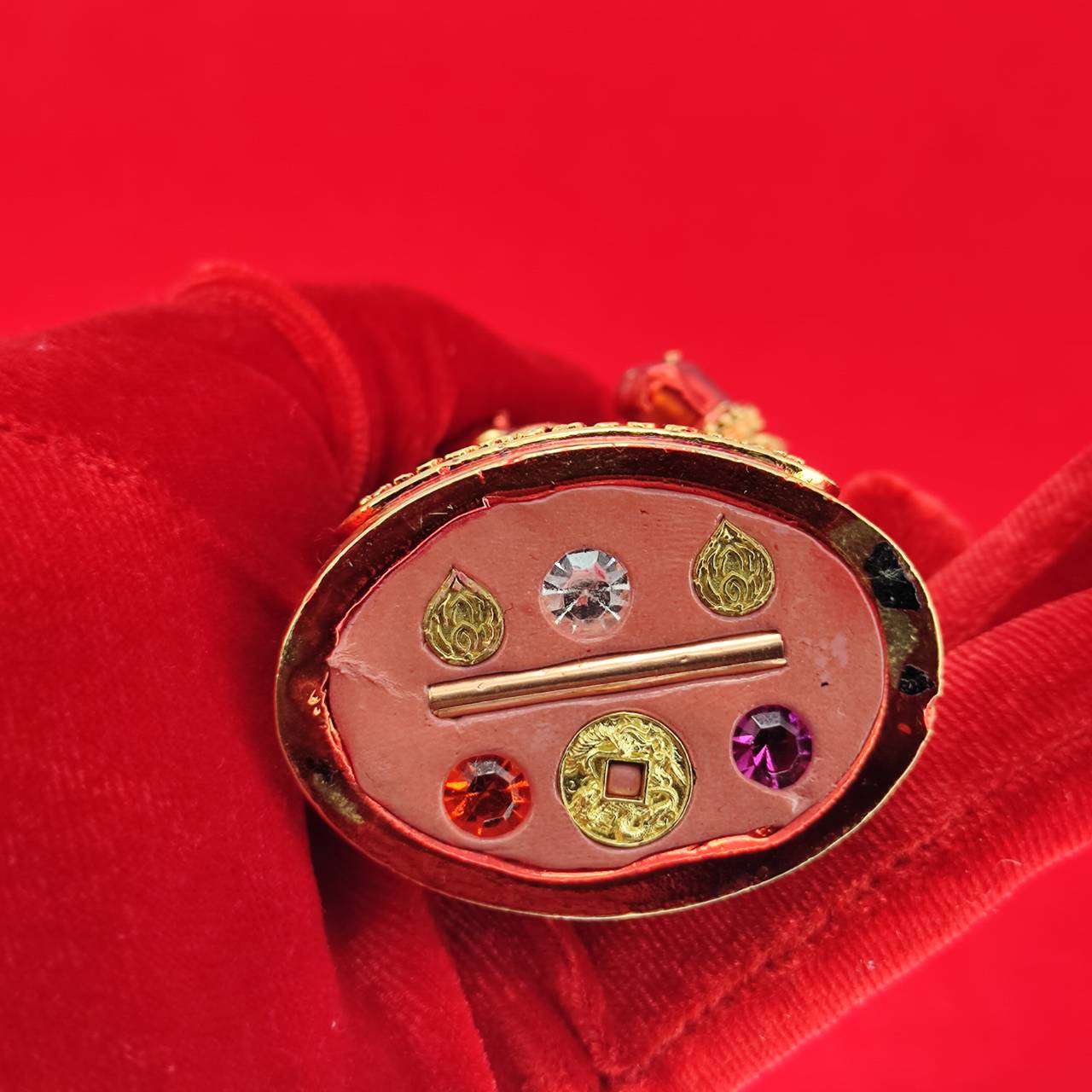 Lord Vesuvanna lucky charm figurine featuring vibrant gemstones and intricate details on a red background