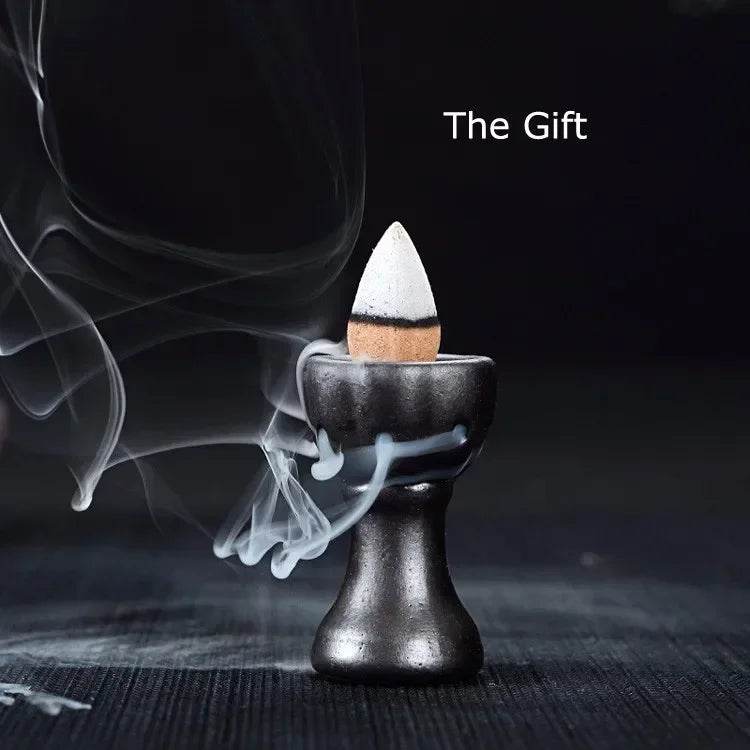 Black ceramic backflow burner with sandalwood backflow incense cones producing cascading downward smoke