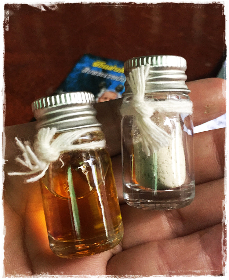 Maha Long Charm Oil and Aok Tak Powder in small glass bottles for spiritual use