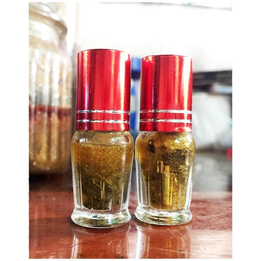 Two bottles of Maha Phokasap oil for luck and wealth on a wooden surface, enhancing prosperity vibes