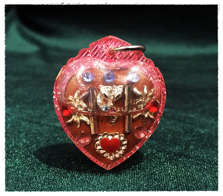 Heart shaped pink Thai amulet for love and fortune with gold tone charms red heart gem and blue stones