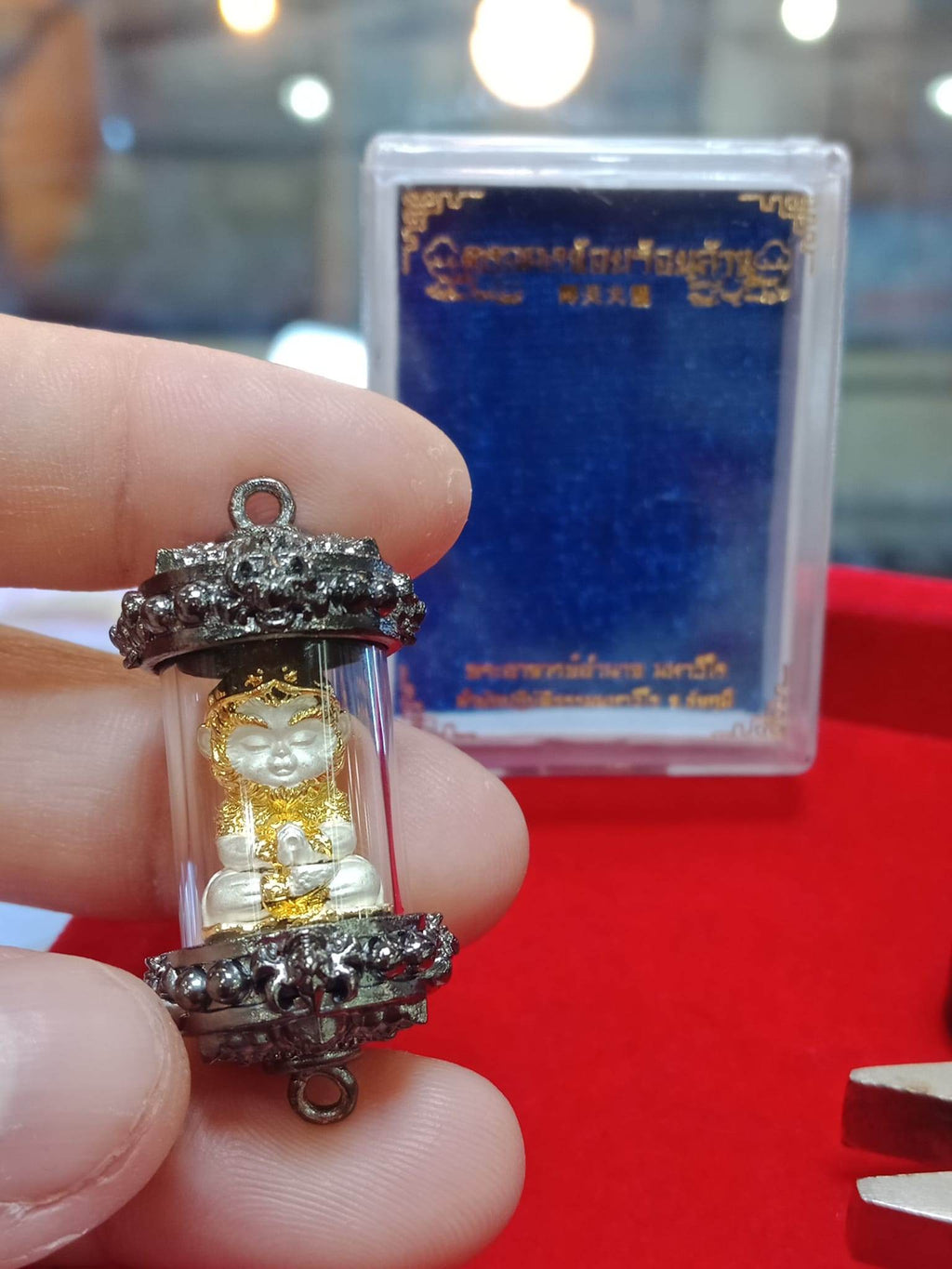 Monkey King fortune amulet encased in protective glass with intricate detailing and a blue background