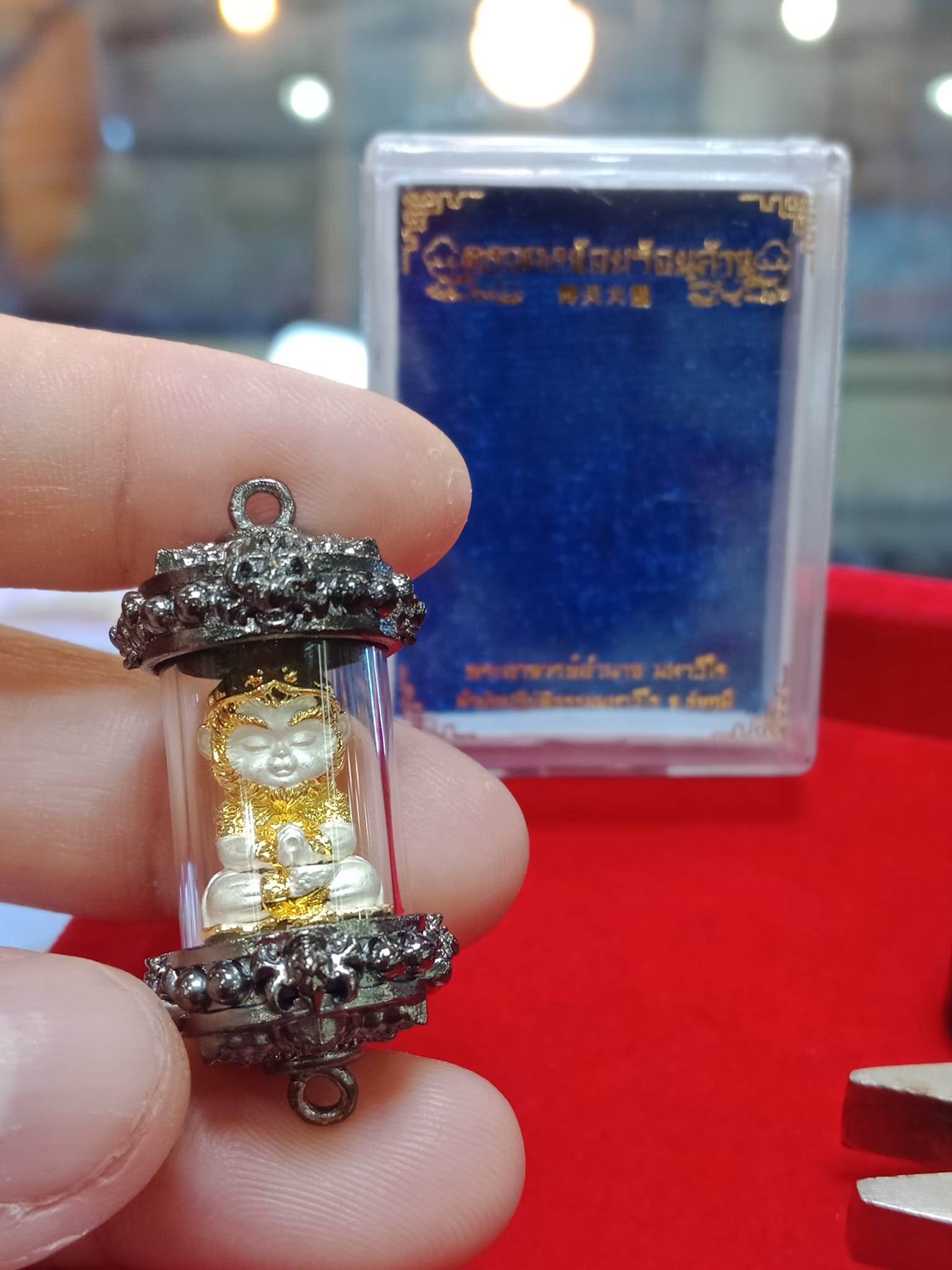 Monkey King fortune amulet encased in protective glass with intricate detailing and a blue background