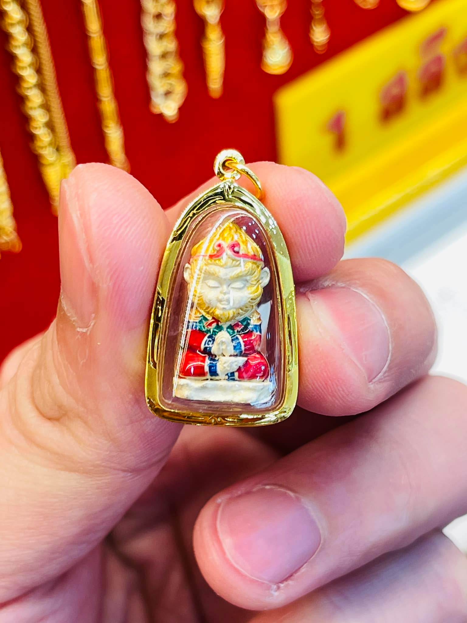 Handheld Monkey King fortune amulet encased in gold, representing prosperity and protection