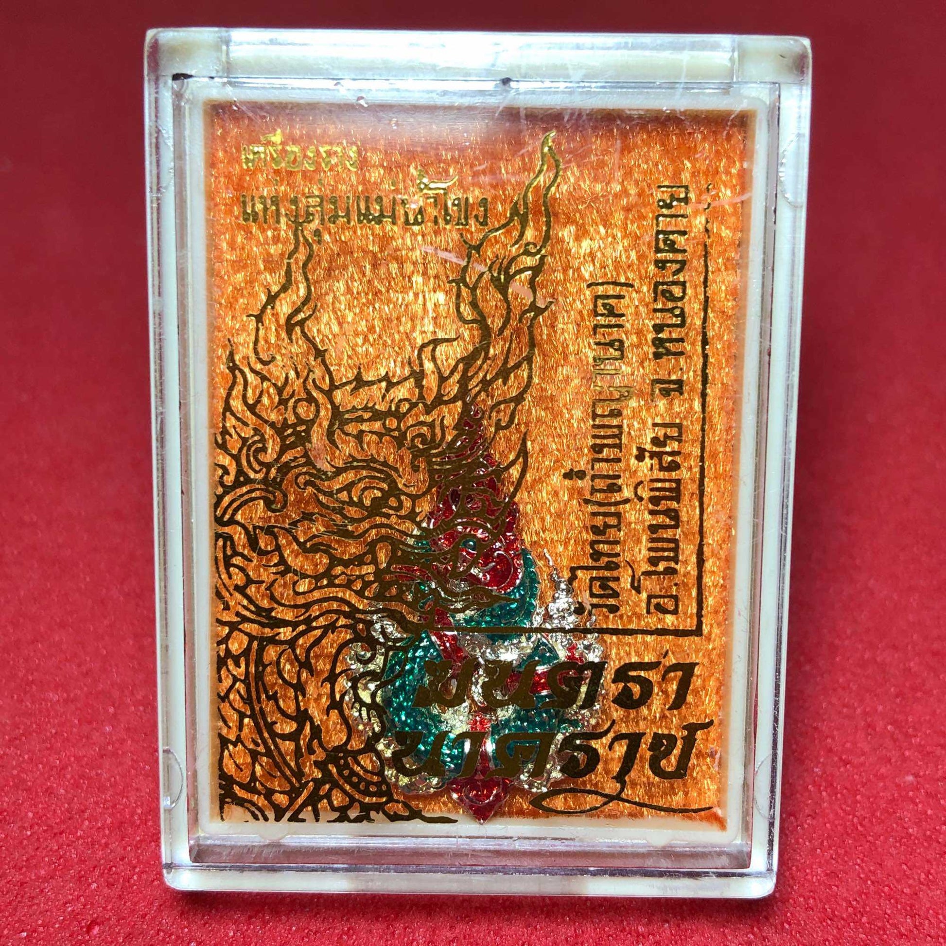 Naga amulet for wealth and protection encased in a protective display cover with intricate design
