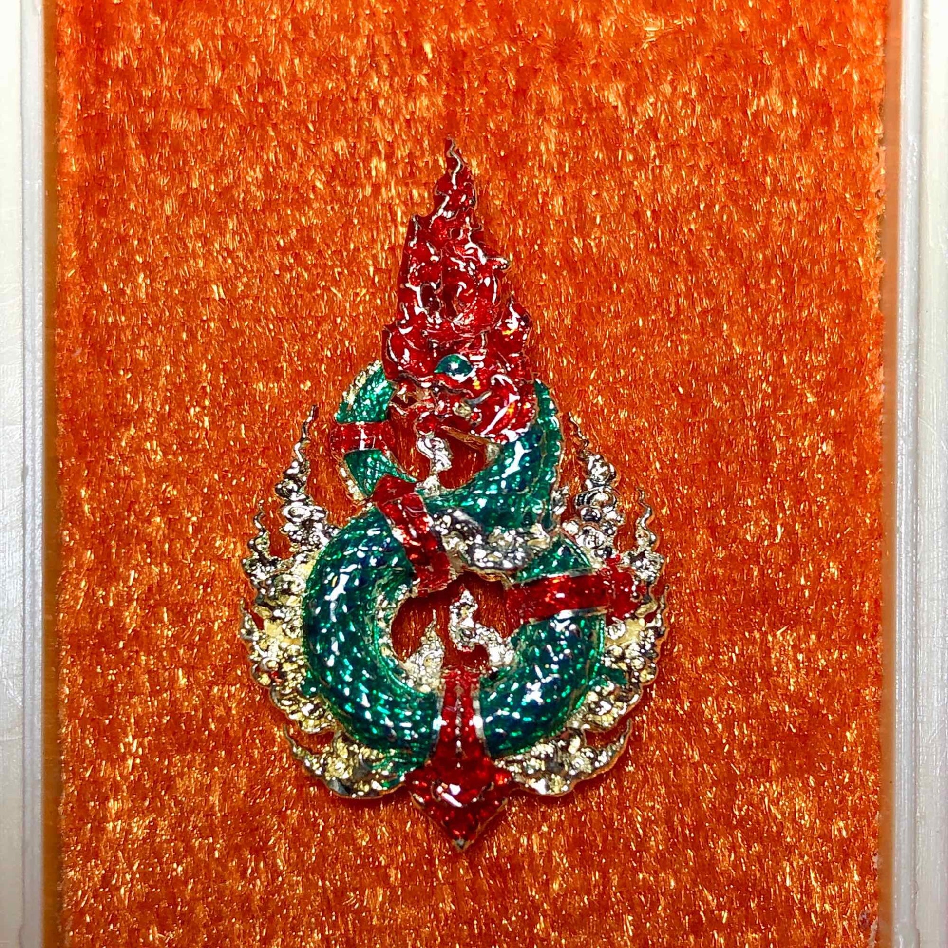 Colorful Naga amulet for wealth and protection displayed on an orange background