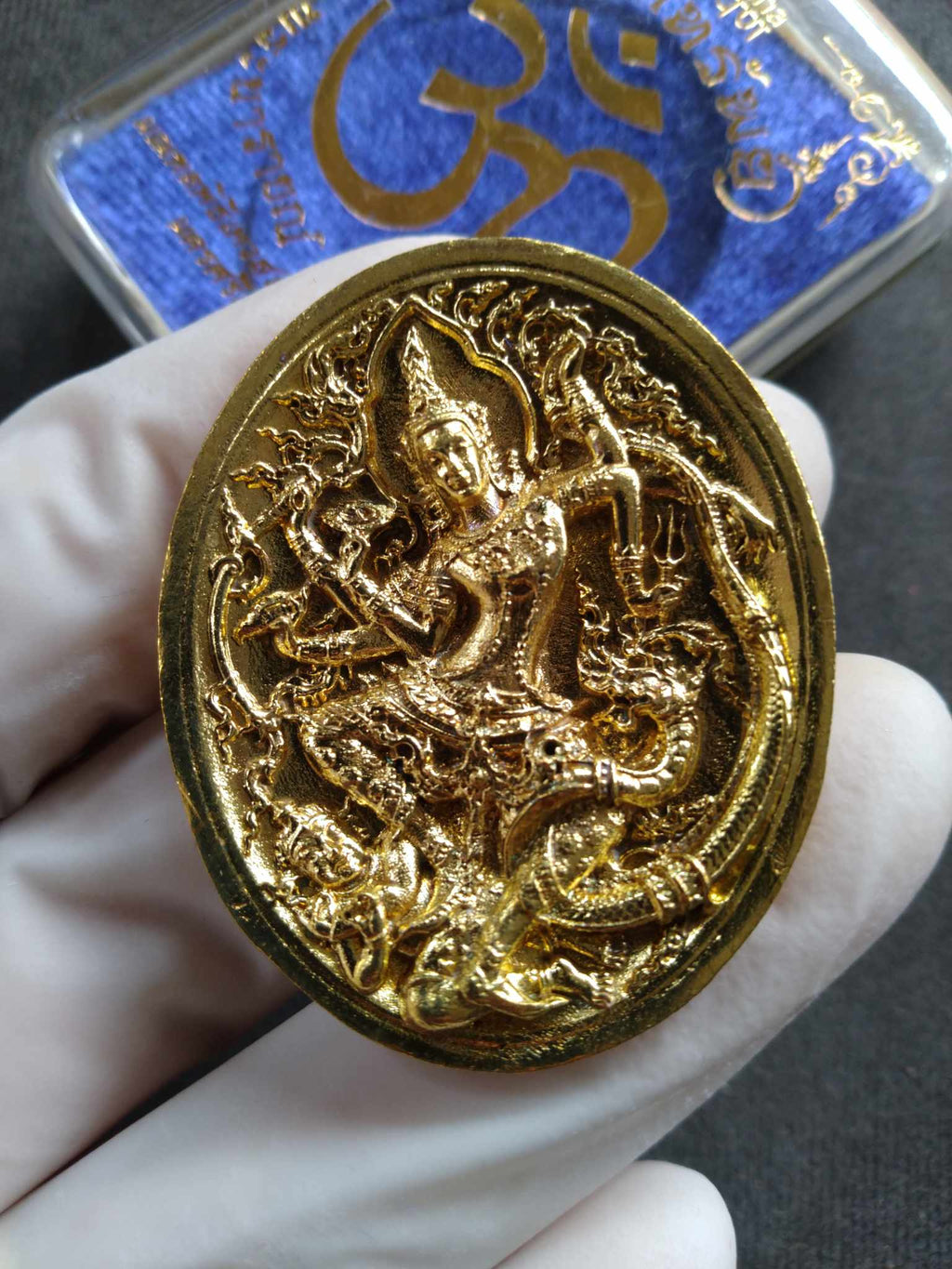 Narai the Great amulet gold oval Thai deity intricate relief held in gloved hand by Thai Blessing Co