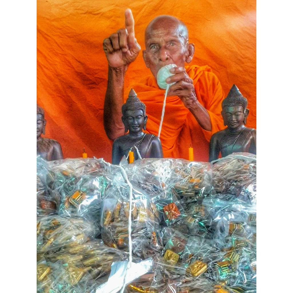 Thai monk blessing Narayana on Garuda amulet with Buddha statues and amulets packaged in plastic bags