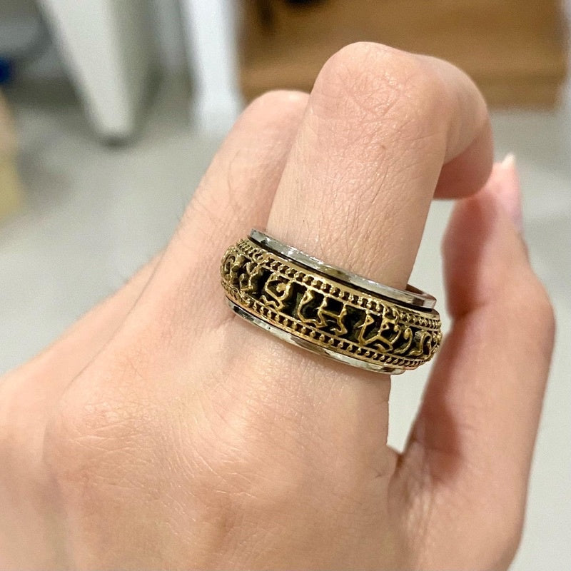 Intricate Thai Buddhist amulet jewelry ring with detailed gold and black design worn on finger