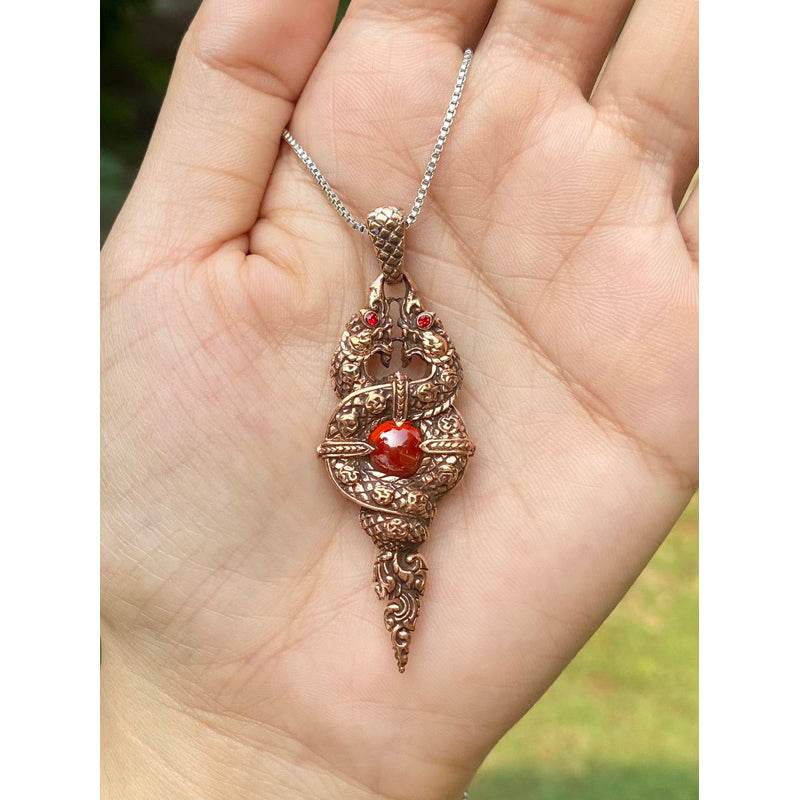 Naga wealth elevation amulet bronze serpent pendant with red gemstone held in hand on silver chain