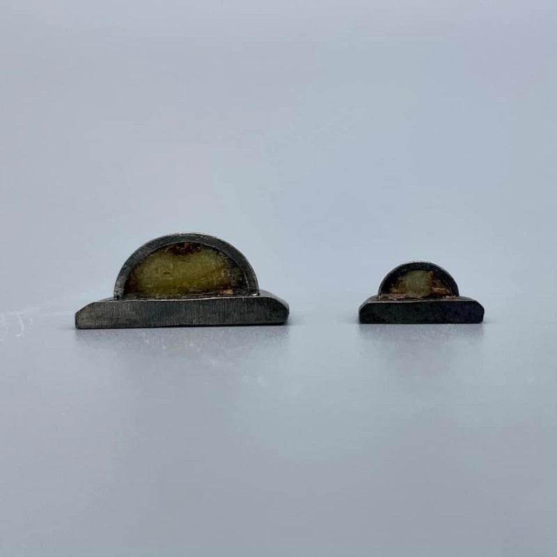 Phaan Thai luck amulet set two small semicircular metal amulets with resin centers on white background for home blessing