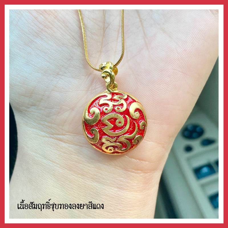 Naga treasure amulet Thailand gold plated red enamel round pendant with swirling naga design on chain held in hand
