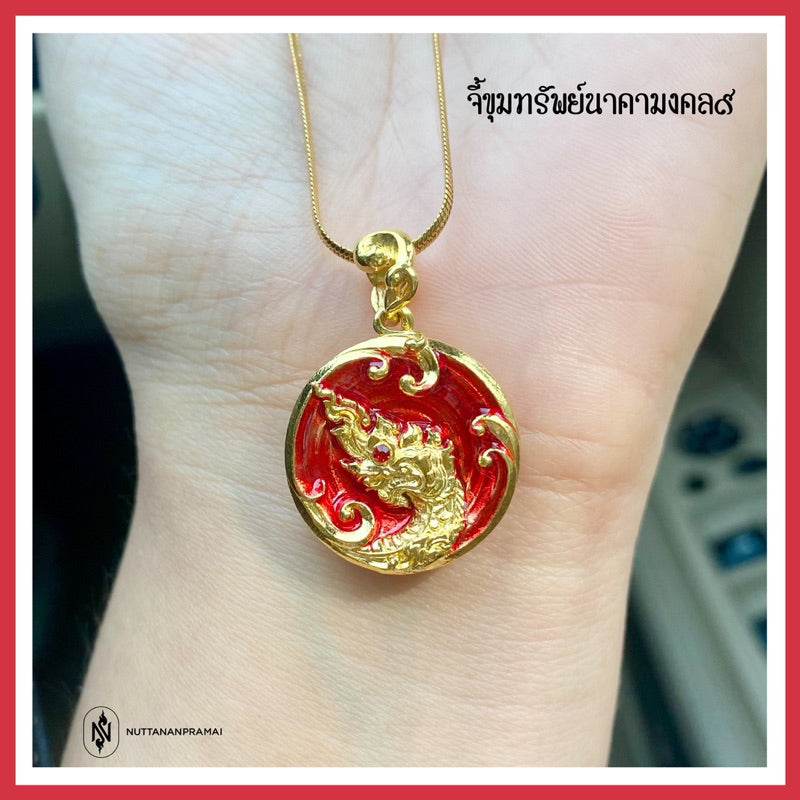 Naga treasure amulet Thailand gold round pendant with red enamel Naga motif on gold chain held on wrist