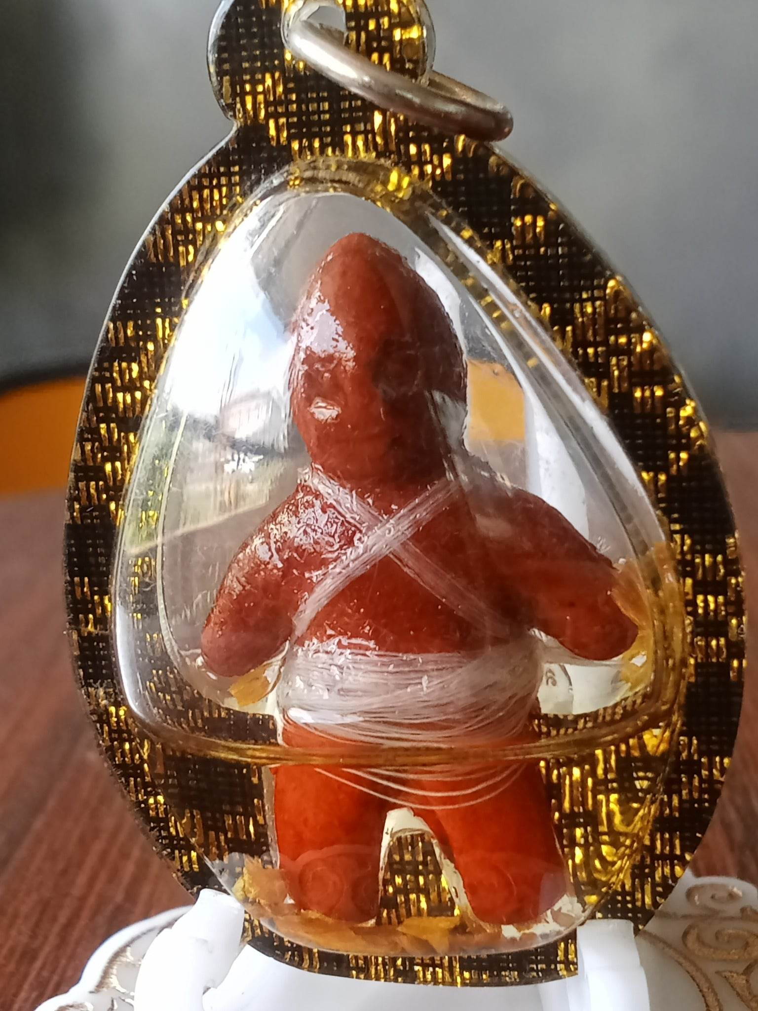 Oil-wrapped spirit doll for protection encased in a gold and black decorative pendant by Thai Blessing Co
