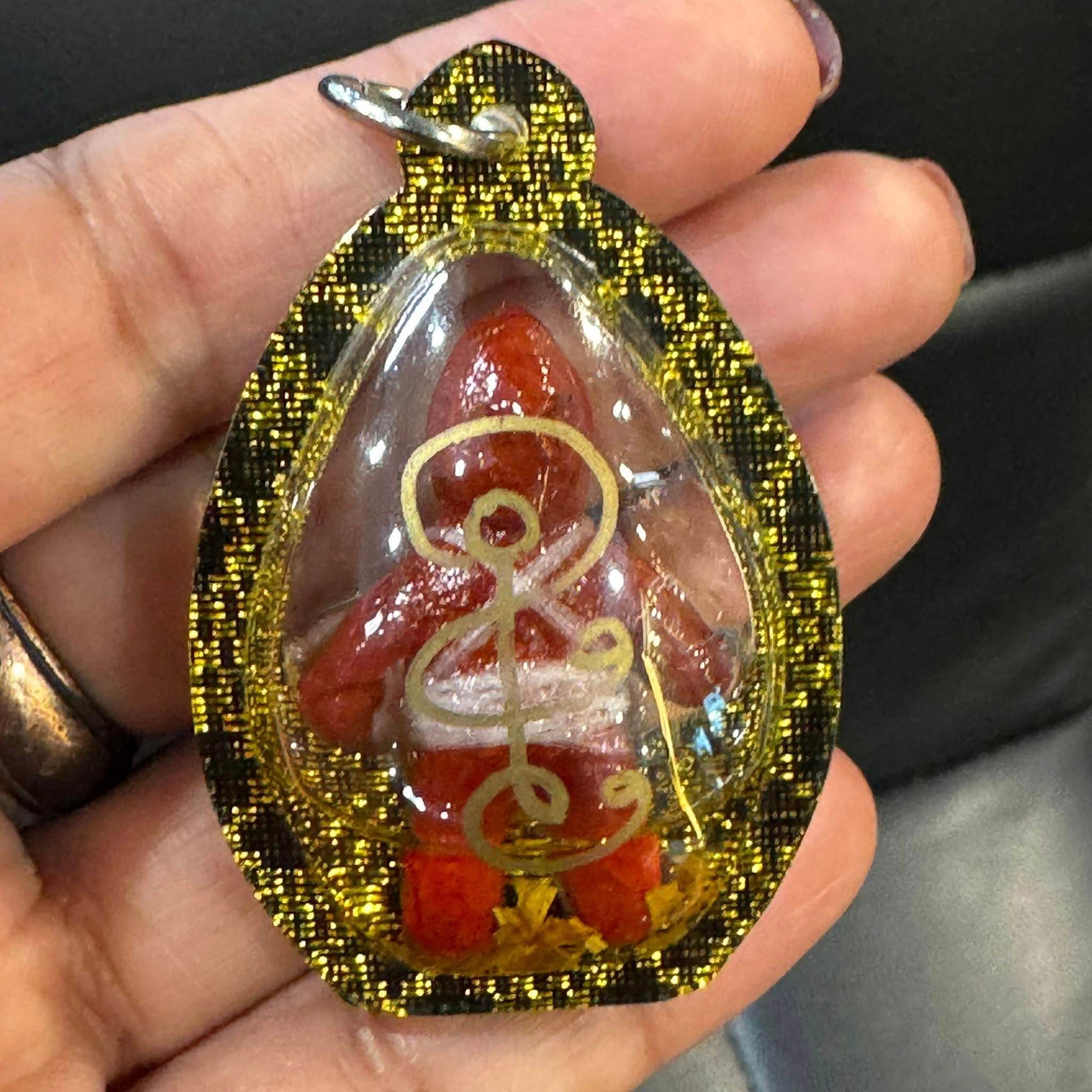 Oil-wrapped spirit doll for protection with intricate gold details in a protective clear casing