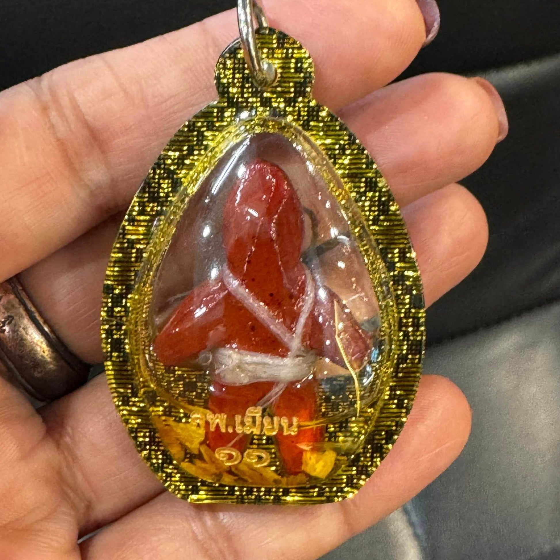 Thai Blessing Co oil-wrapped spirit doll for protection encased in yellow checkered amulet frame held in hand
