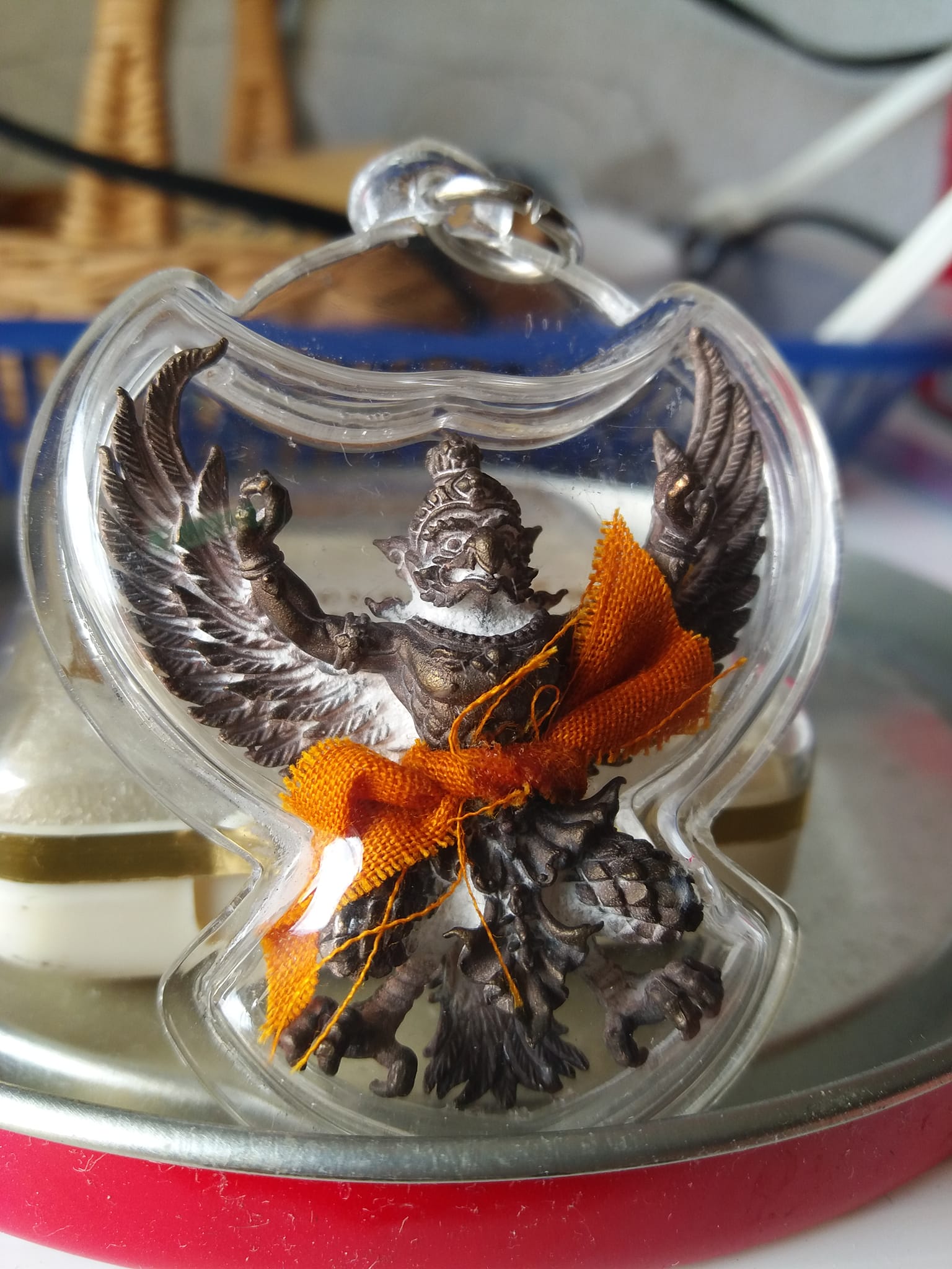 Phaya Garuda amulet for sale encased in clear plastic with detailed wings and orange cloth