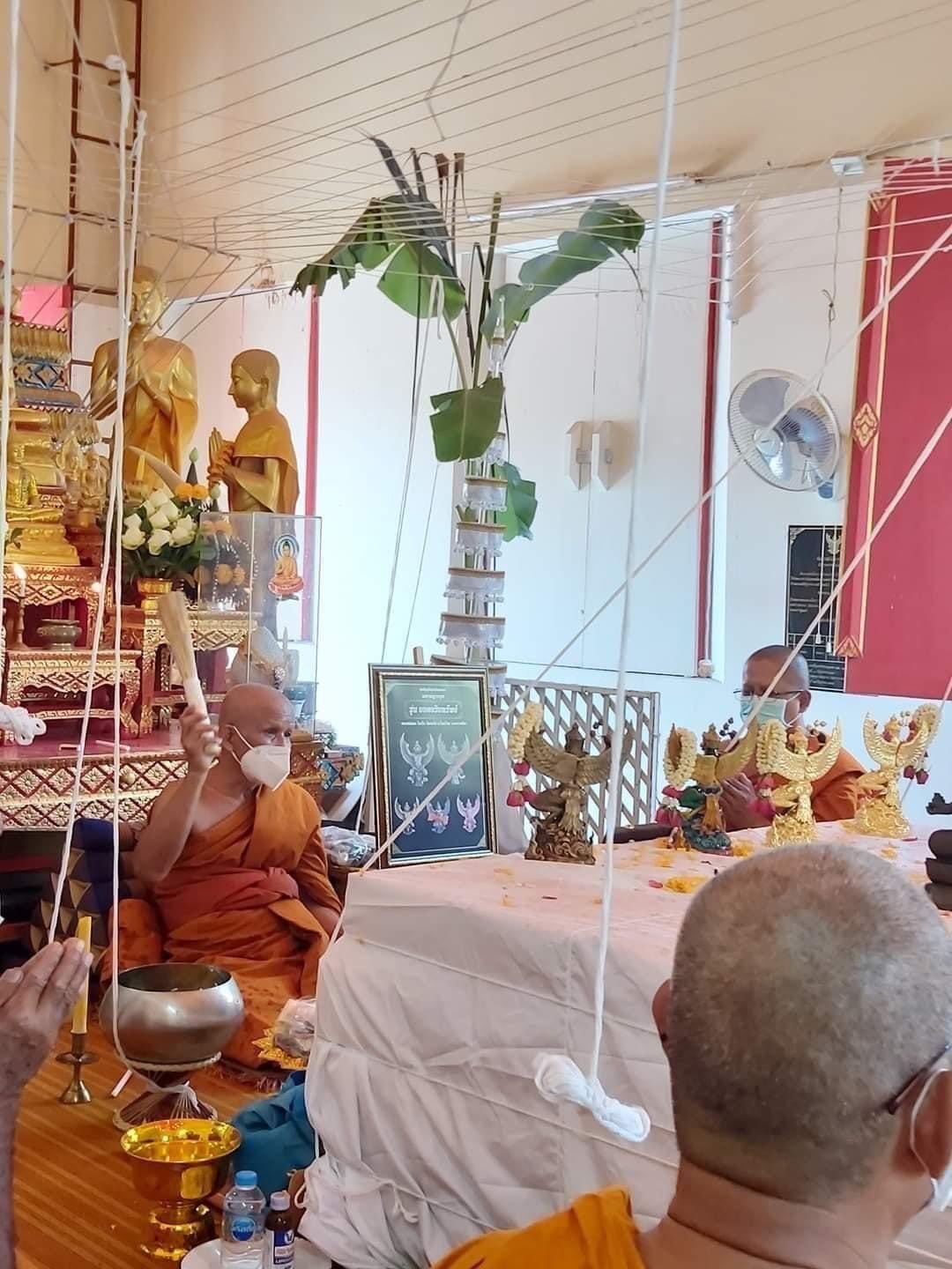 Phaya Garuda amulet for sale displayed during a Buddhist ceremony with monks in traditional robes