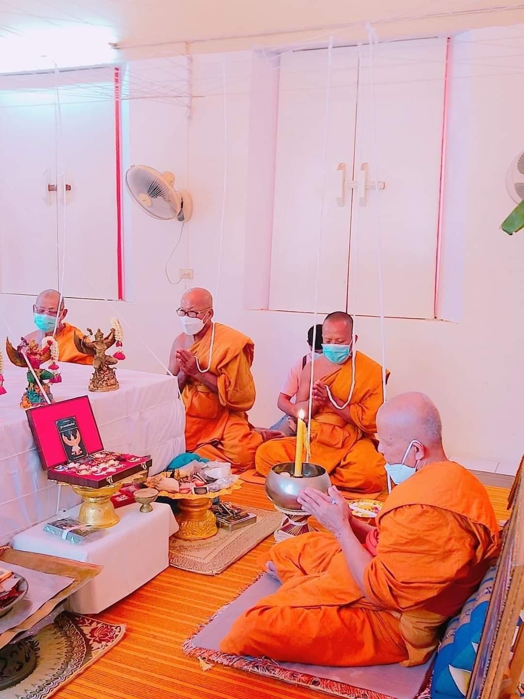 Thai monks in orange robes performing a religious ceremony with a Phaya Garuda amulet for sale displayed on a table