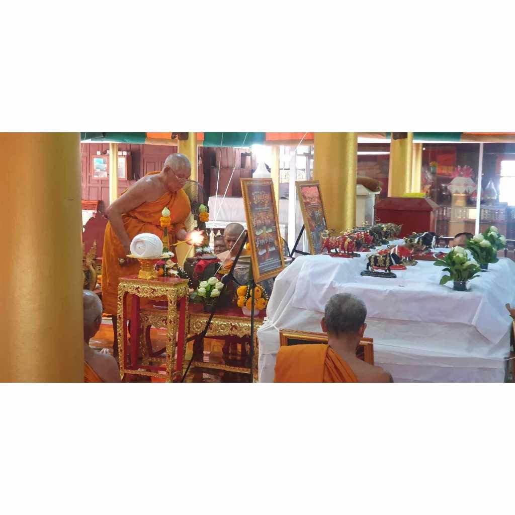 Monks performing a ritual ceremony with Phaya Waraha Racha Chok power talisman displayed on altar in temple