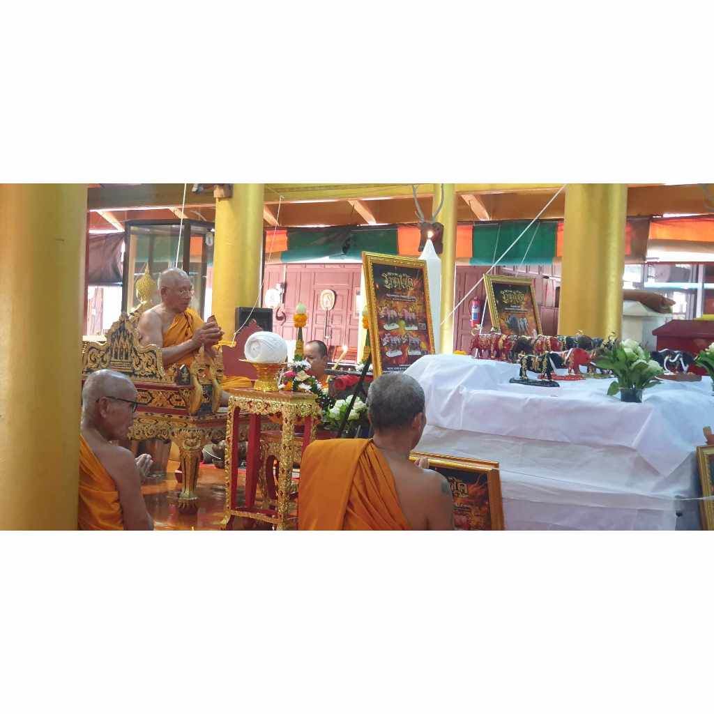 Phaya Waraha wealth charm displayed in a religious ceremony with monks in traditional orange robes