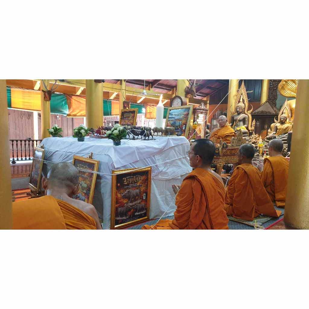Thai monks praying inside temple with Phaya Waraha wealth charm and religious artifacts
