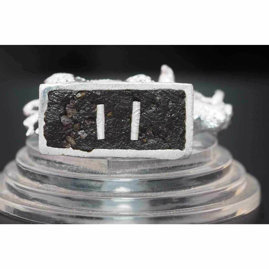 Close-up of Phaya Waraha wealth charm with black textured surface and silver frame by Thai Blessing Co