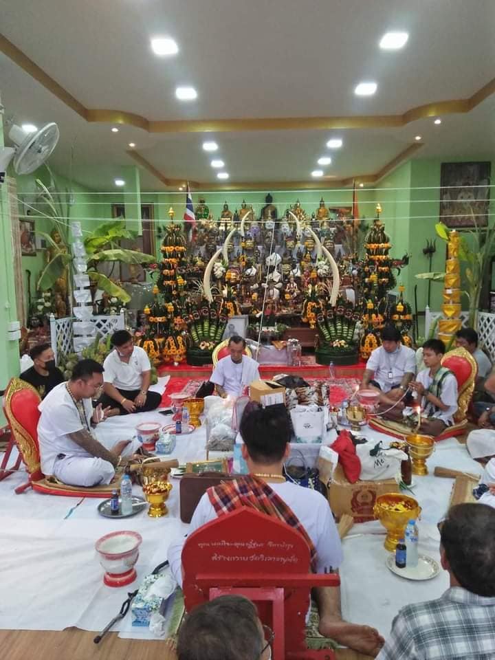 Thai blessing ritual with devotees offering garlands and gold bowls around Phayak Naree tiger goddess amulet shrine