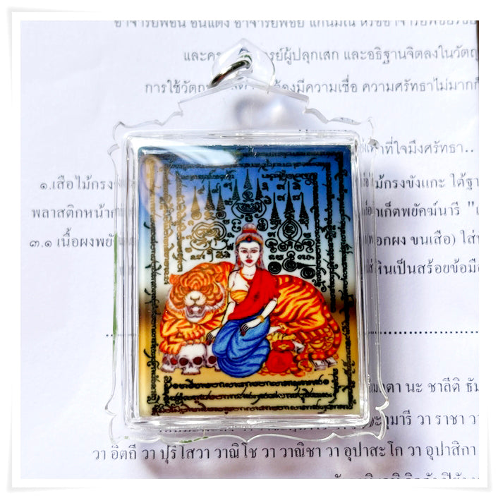 Phayak Naree tiger goddess amulet clear plastic pendant showing seated goddess with tiger skulls and script