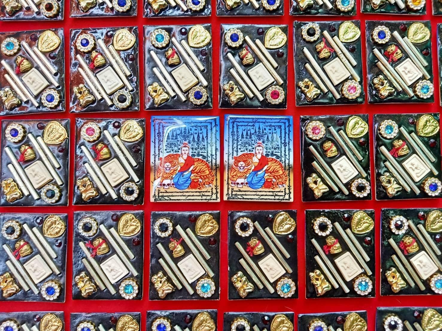 Rows of colorful boxed Phayak Naree tiger goddess amulet displays with gold accents and jeweled decorations
