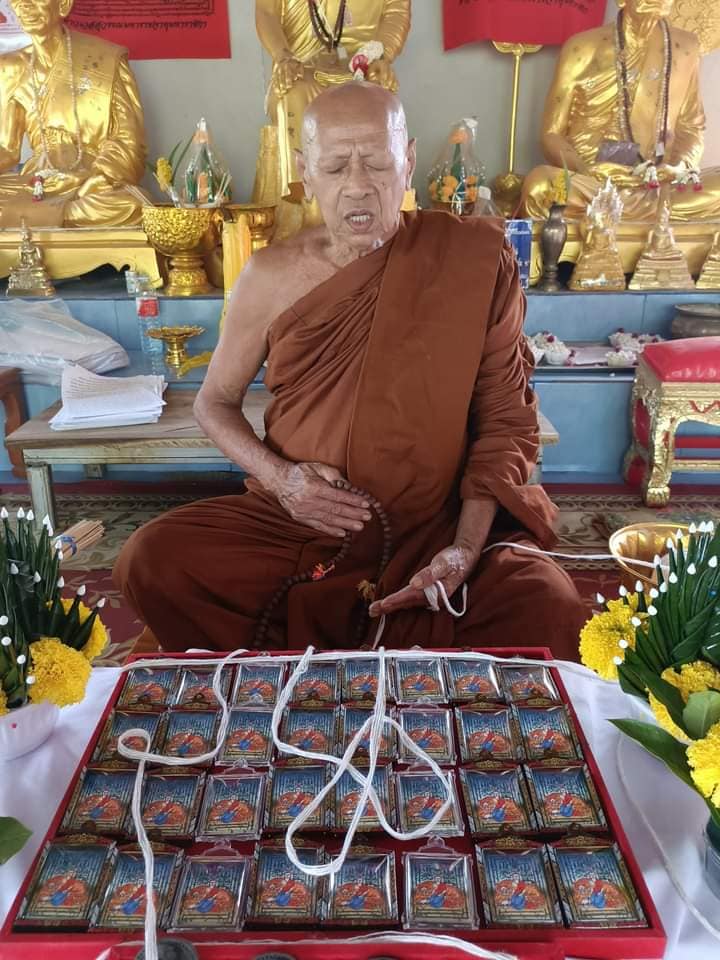 Phayak Naree tiger goddess amulet tray displayed before seated Thai monk in temple with Buddha statues