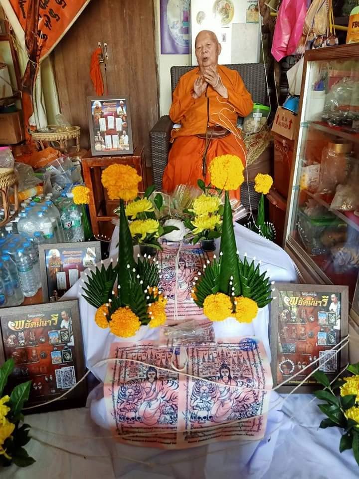 Phayak Naree tiger goddess amulet displayed on ceremonial cloth with tiger prints marigold offerings and monk in orange robes