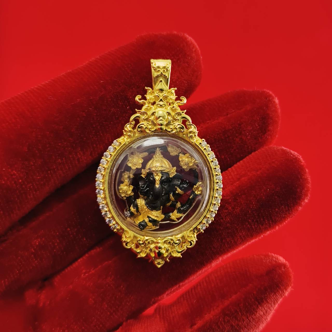 Gold Phra Brahma amulet for protection with intricate detailing and clear casing displayed on a red background