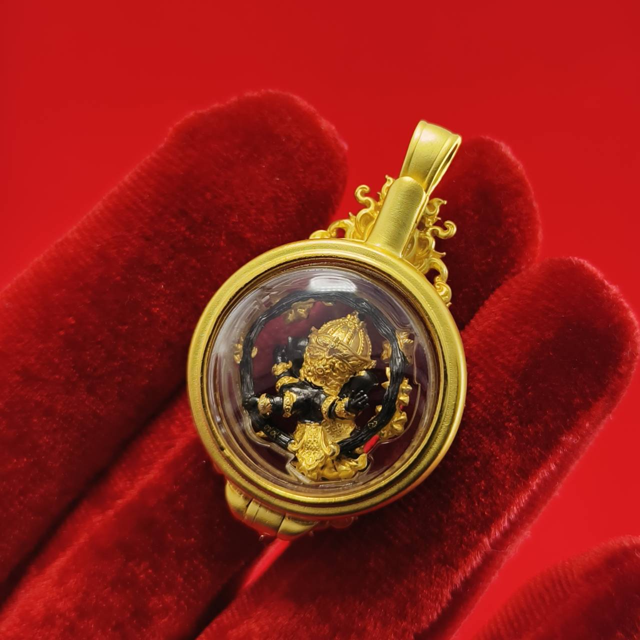 Phra Brahma amulet for protection in a gold setting, displayed against a red background